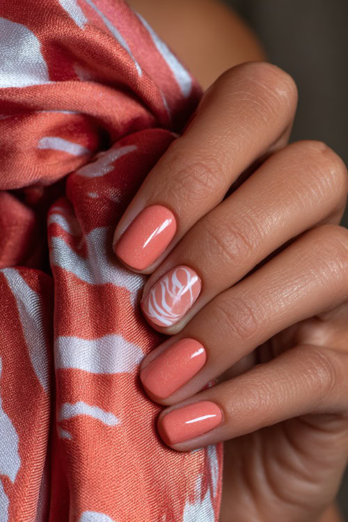 Bride’s hand gently holding silk fabric, short ballerina nails in pastel coral with shimmer overlay and one accent nail with white swirl design 