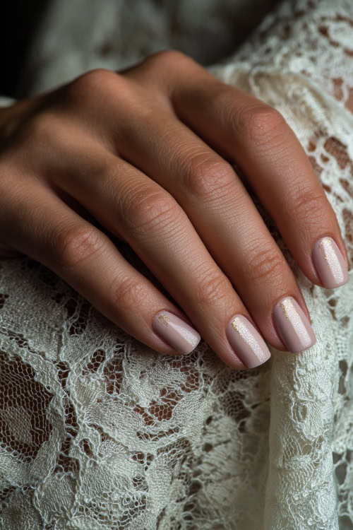 Bride’s hand resting on vintage lace fabric, square nails in soft rose-beige with satin finish and tiny gold foil flakes on the ring fingers 