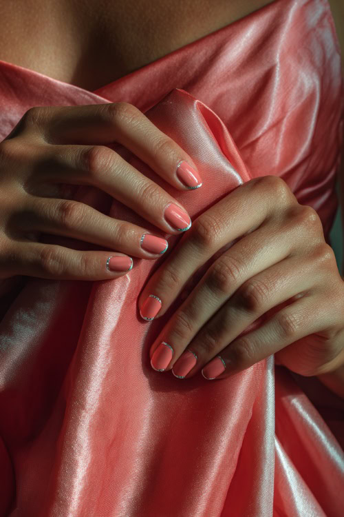 Bridesmaid’s fingers brushing silk dress fabric, medium square nails in pastel coral with chrome French tips and tiny silver crystals near the base