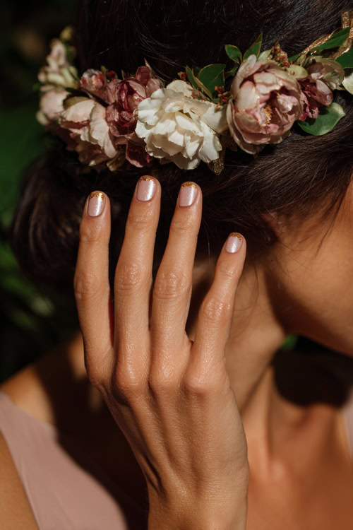 Bridesmaid’s hand adjusting floral headpiece, short ballerina nails in creamy blush with chrome shimmer overlay and tiny gold flakes along the base