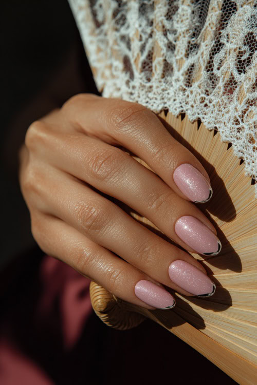Bridesmaid’s hand holding a lace fan, ballerina-shaped nails in pale mauve with glossy finish and chrome French tips for an elegant, modern look 