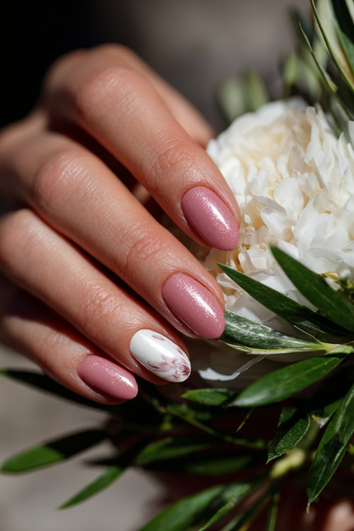 Bridesmaid’s hand placing a corsage, almond nails in soft pink with chrome shimmer and one accent nail in white floral stamping