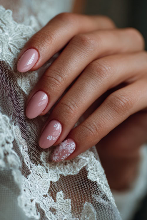 Close-up of bride’s hand gently holding a lace veil, almond-shaped nails in soft blush pink with glossy finish and delicate white floral decals