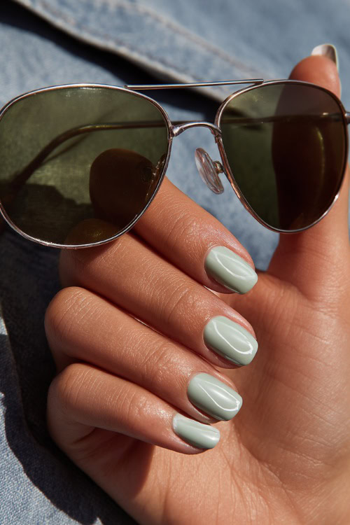 Close-up of bridesmaid’s hand adjusting sunglasses, short square nails in pastel green with gloss finish and minimalist white swirl detail