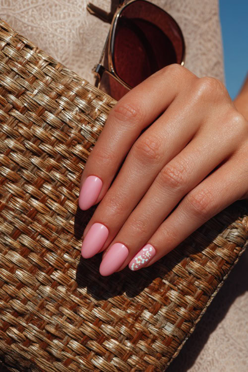 Close-up of guest’s hand holding a woven clutch, short almond nails in pastel pink with glossy finish and tiny white floral decals on two fingers 
