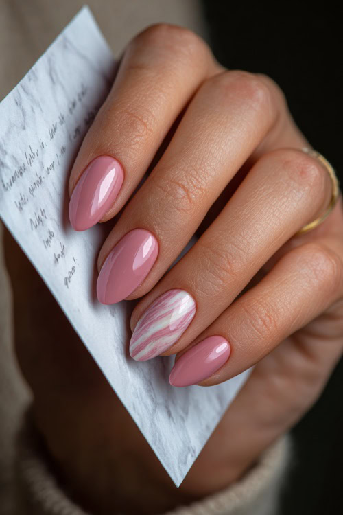 Close-up of hand holding a handwritten note, almond nails in pastel pink with glossy finish and delicate white swirl detailing on one accent nail 