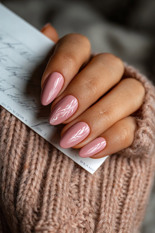 Close-up of hand holding a handwritten note, almond nails in pastel pink with glossy finish and delicate white swirl detailing on one accent nail