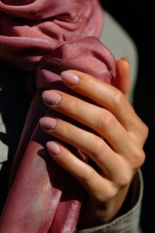 Close-up of hand holding a silk scarf, short ballerina nails in pastel rose with chrome shimmer tips and delicate crystal details