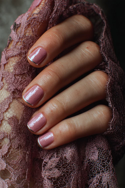 Close-up of hand holding lace glove, short square nails in light pink with glossy topcoat and a thin silver line across the center of each nail 