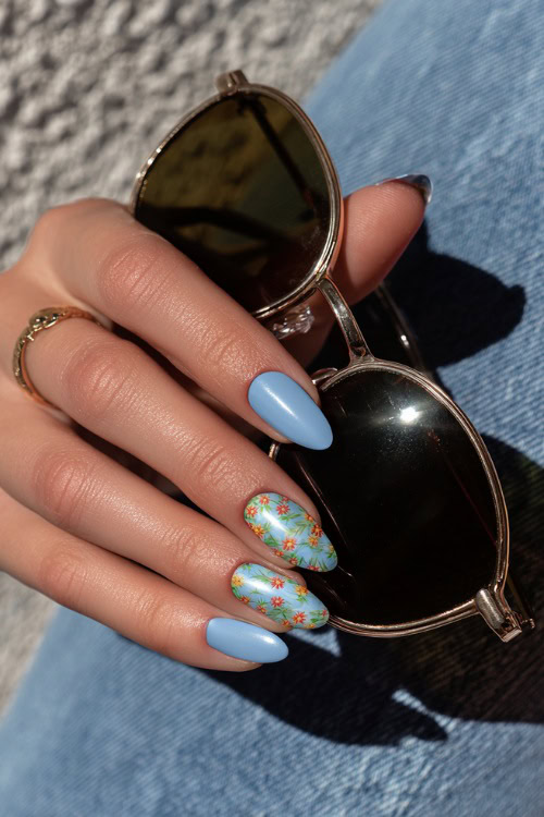Elegant guest’s hand holding sunglasses, short almond nails in pastel blue with chrome finish and minimalist floral pattern on two fingers