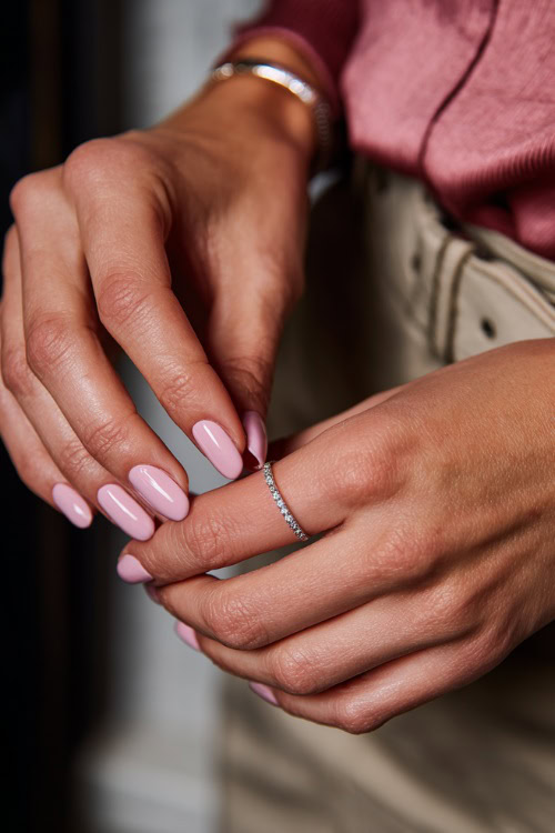Elegant hand adjusting a bracelet, medium ballerina nails in pastel pink with glossy finish and tiny crystal accents on each ring finger