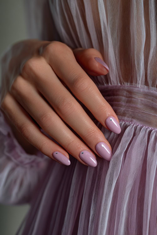 Elegant hand gently brushing chiffon dress, oval nails in pale lilac with glossy topcoat and minimal silver dot near the cuticle