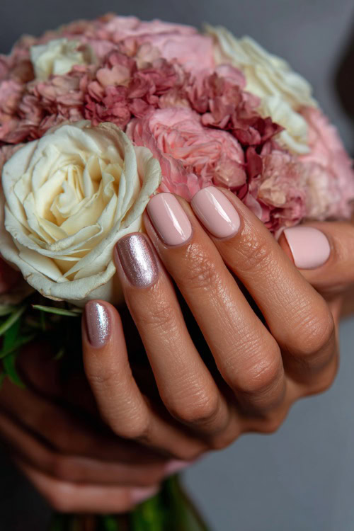 Elegant hand holding a pastel rose bouquet, square nails in sheer ivory with glossy finish and delicate silver leaf foil on two fingers 