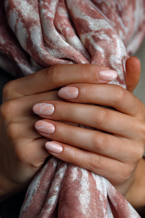 Elegant hand holding silk scarf, short almond nails in pastel peach with marble texture and delicate silver foil accents
