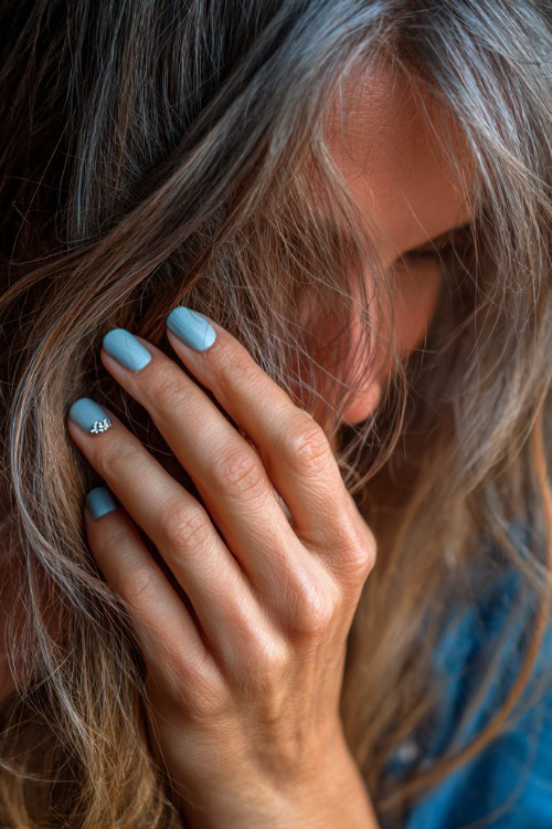Guest’s fingers brushing through loose hair, pastel blue short square nails with shimmer finish and tiny white heart on each ring finger 