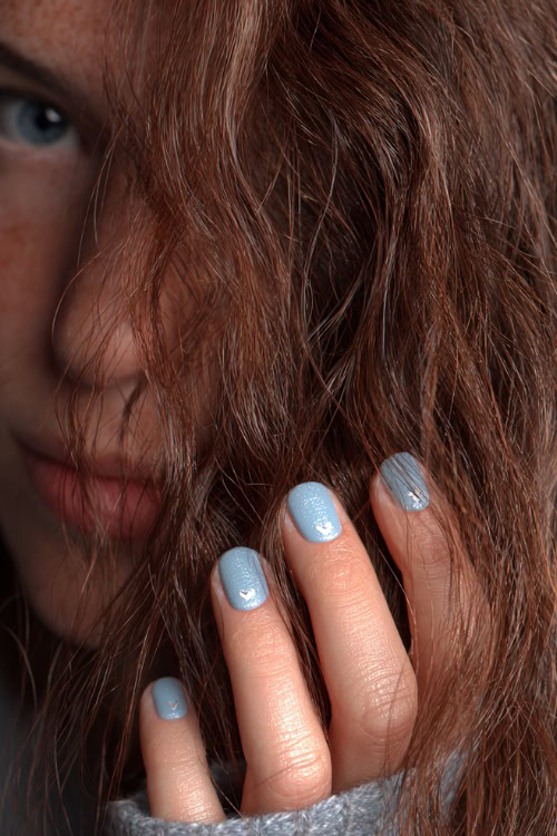Guest’s fingers brushing through loose hair, pastel blue short square nails with shimmer finish and tiny white heart on each ring finger