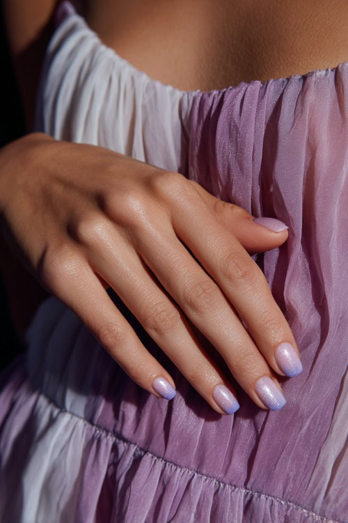 Guest’s hand gently brushing chiffon dress, short rounded nails in pastel lavender with silver glitter ombré fade on the tips 