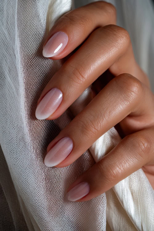 Hand adjusting veil, short almond nails in sheer ivory with shimmer fade toward the tips and clear glossy finish