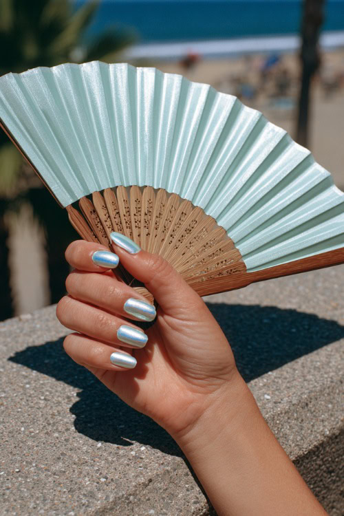 Hand holding a wedding program fan, medium almond nails in pastel mint green with chrome French tips and one accent nail featuring daisy art 